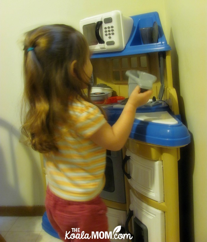 Three-year-old playing at her toy kitchen
