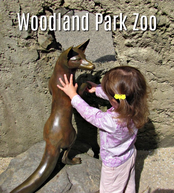 Toddler petting a statue at the Woodland Park Zoo.