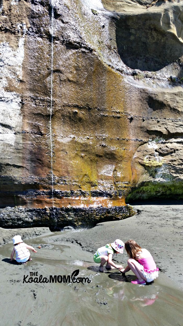 Three girls building a dam in a stream at Mystic Beach