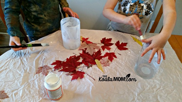 The girls apply Mod Podge and fall leaves to their vases
