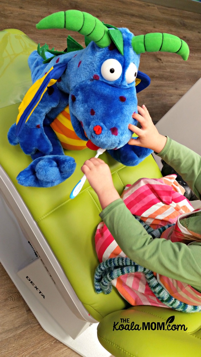 Jade brushing a stuffed dino's teeth at Smiletown Dentistry