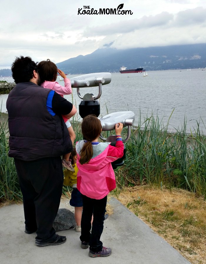 Daddy and daughters peer through binoculars to the ocean at Jericho Beach.