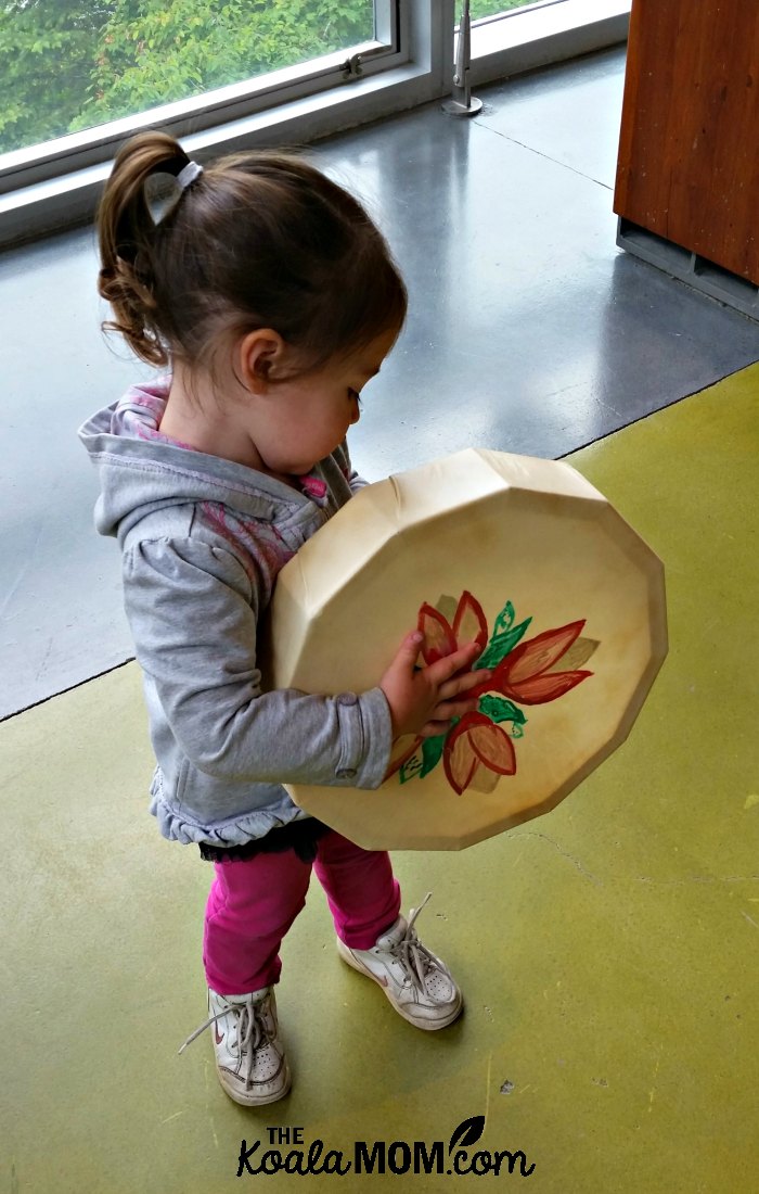 Toddler holding an aboriginal drum at the Squamish Lil'wat Cultural Centre in Whistler, BC.