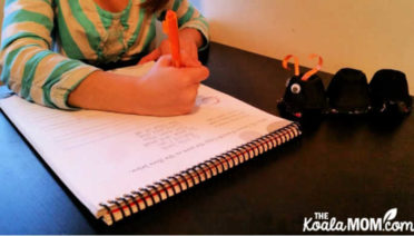 Grade 1 student doing handwriting with her egg carton ant watching.