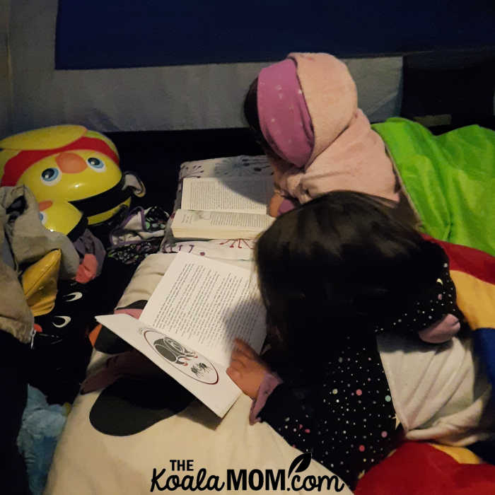 An 8-year-old and 5-year-old read their books in the tent.