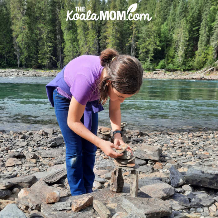 Teenager stacking stones on a beach in Wells Gray Provincial Park.