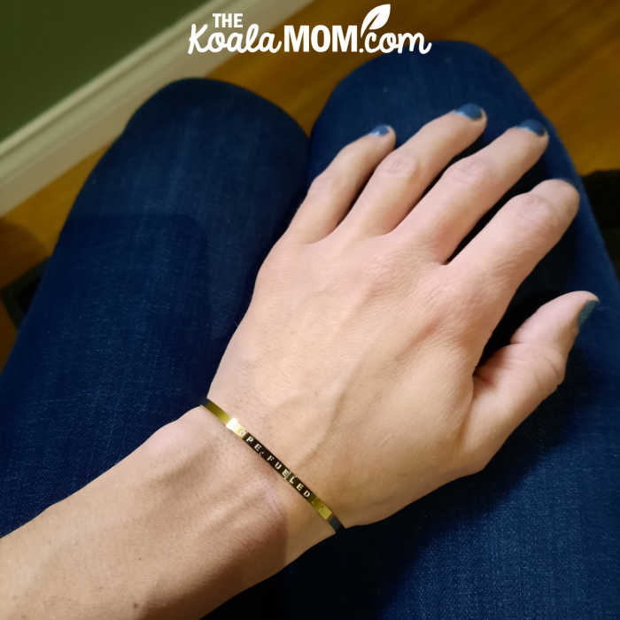 Woman wearing a gold bracelet that says "Hope Fueled."