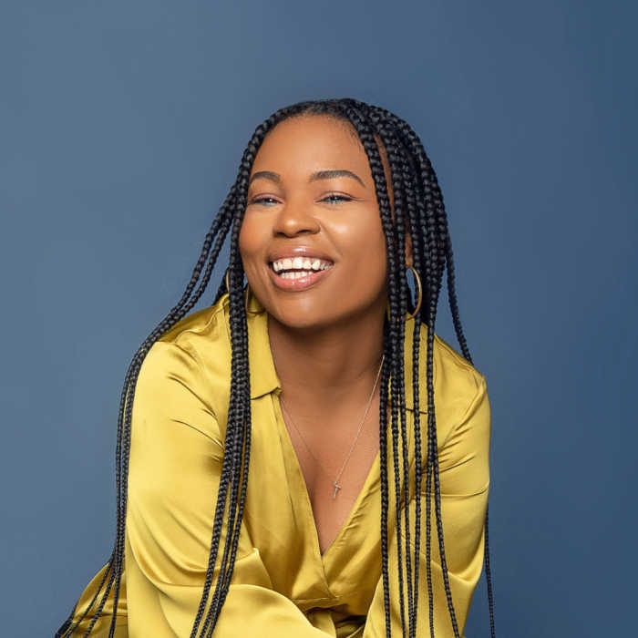 Woman in yellow jacket wearing her long hair in goddess braids. Photo by Tahiti Spears on Unsplash
