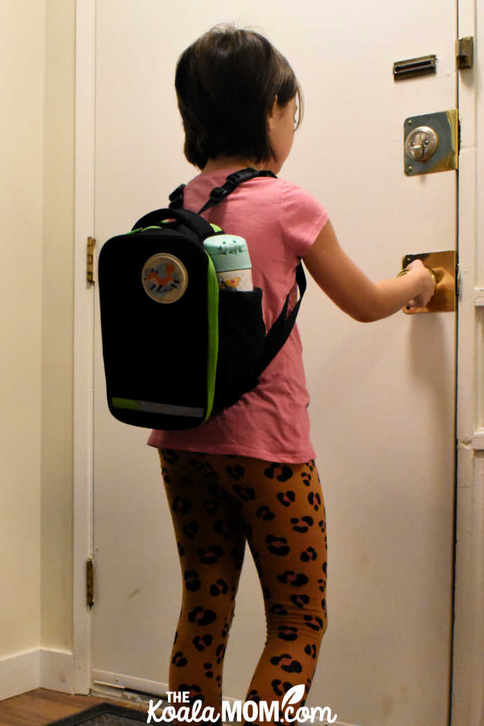 Girl wearing a TiniBag on her back as she heads out the door for homeschool activities.