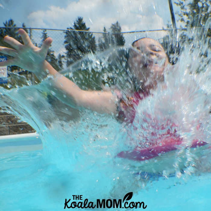 Girl jumps into outdoor pool.