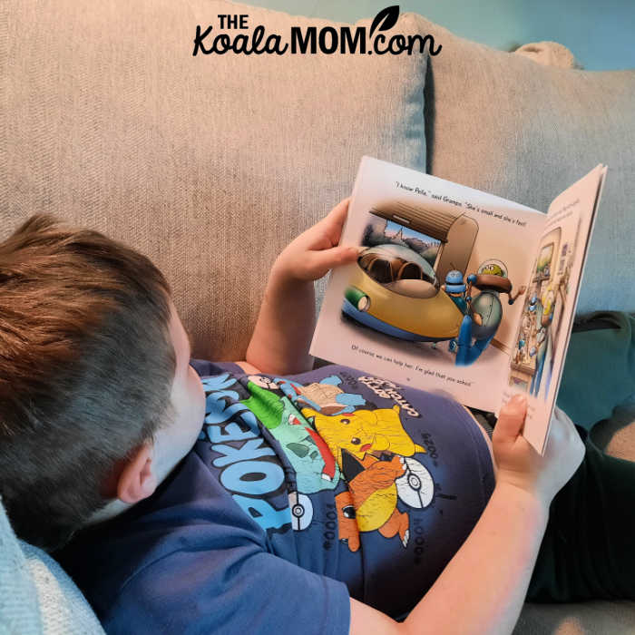 A boy lays on a couch reading Lynn Johnston's picture book A Little Kindness.