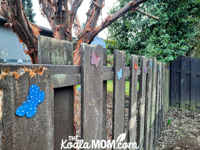 Brightly painted butterflies decorate a brown fence.