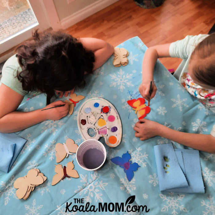 Two girls painting butterflies together.